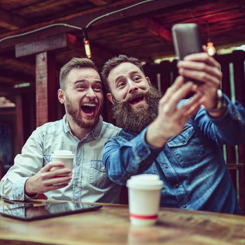 Two Bearded Friends Drinking Coffee and Taking Selfie in Restaurant