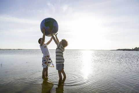 dos niños sosteniendo un globo terráqueo en la playa