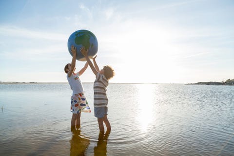 Dos niños sosteniendo un globo terráqueo en la playa dos niños sosteniendo un globo terráqueo en la playa