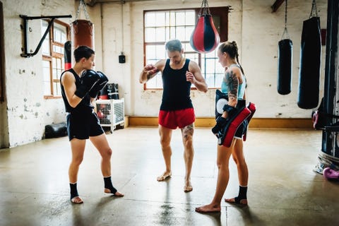 dos luchadoras de muay thai con su entrenador