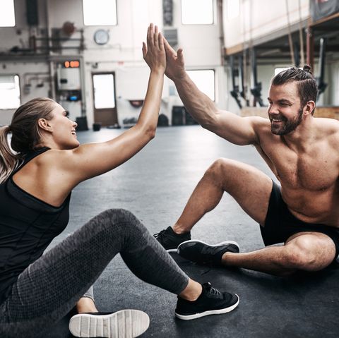 Two fit young people high fiving together after a workout