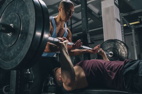 two friends exercising bench press in gym