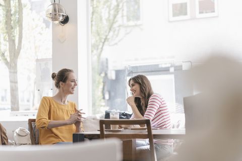 Two girlfriends meeting in a coffee shop, talking