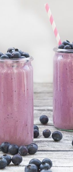 two glasses of blueberry smoothie and blueberries on wood