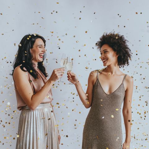 two happy women celebrating new year's eve with a champagne toast under confetti