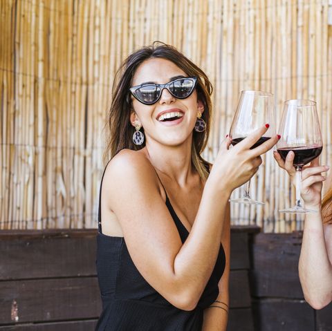 two happy women having a glass of red wine at a bar