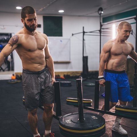 Two muscular men working out in gym