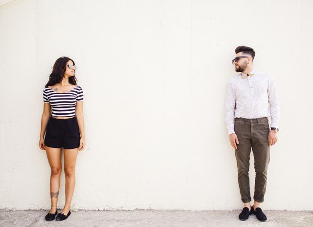 two people standing on white wall background