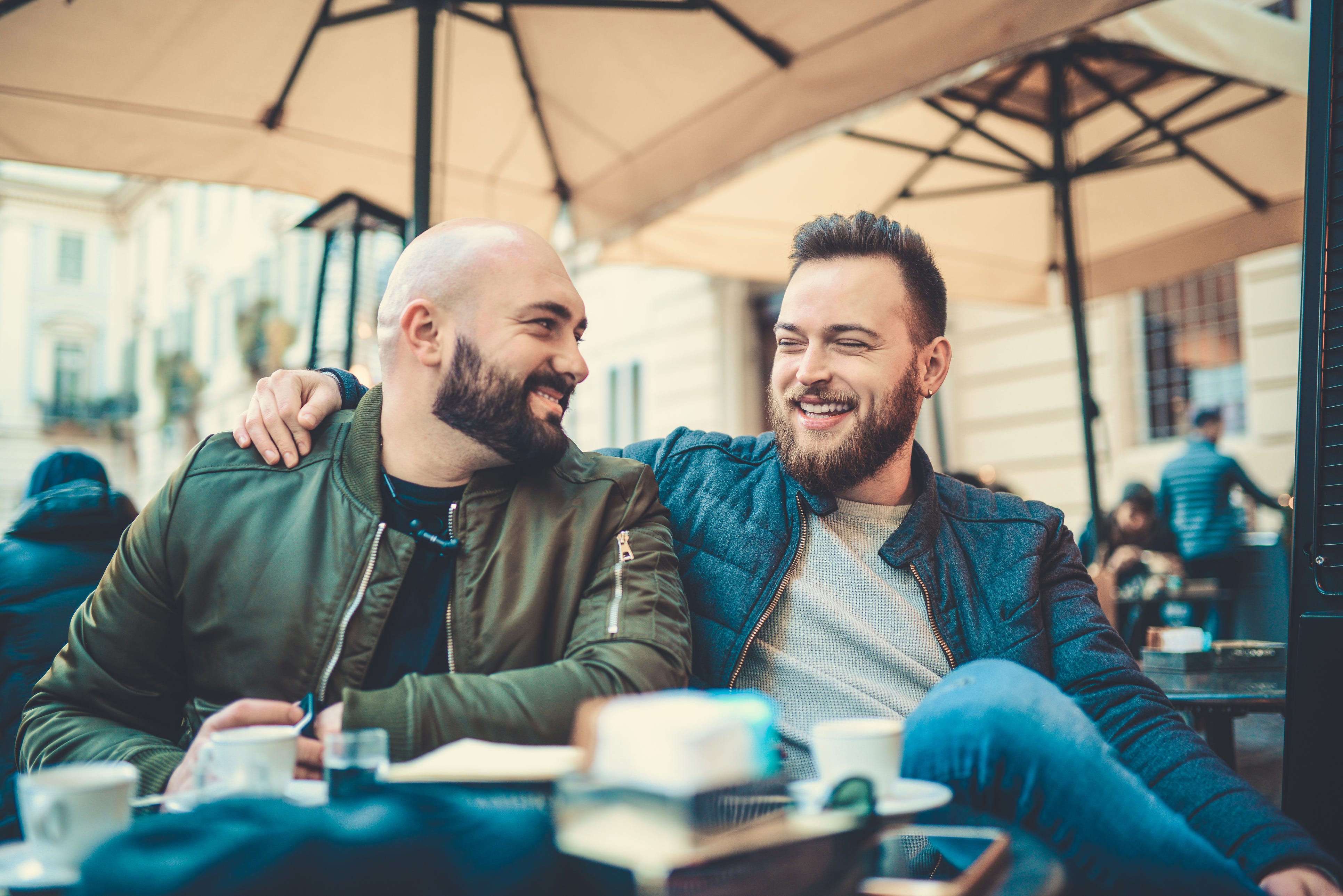 Zwei lächelnde Freunde trinken Kaffee und unterhalten sich in einem Café