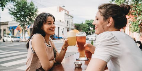 Two women friends sitting at a cafe, doing a celebratory toast together