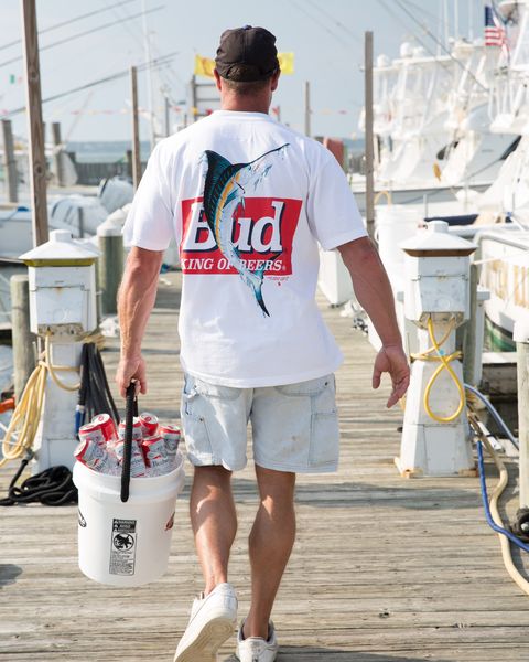 man walking down pier carrying beer wearing the new york sunshine budweiser collection