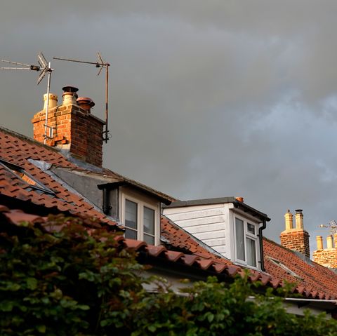 dark rain clouds just before sunset, the roof tops of traditional cottages