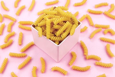Uncooked italian pasta on pink background.