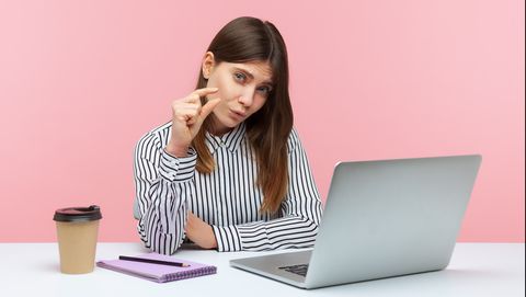 vrouw maakt gebaar voor kleiner achter haar laptop