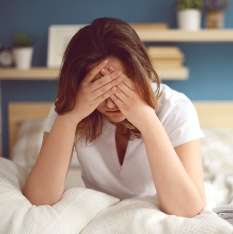 unhappy girl in a bed with hands on her forehead