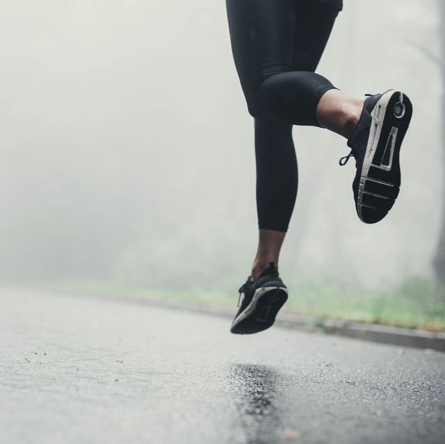 unrecognizable athlete jogging on the road during rainy day