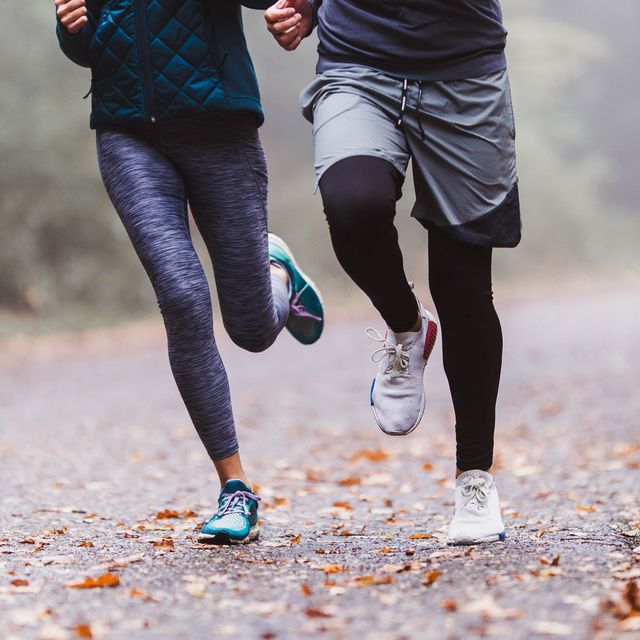 unrecognizable athletic couple running during cold day in forest