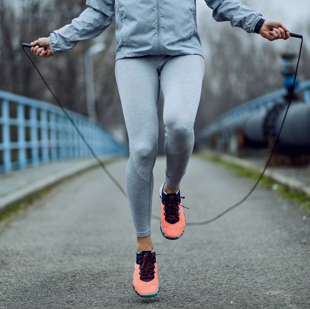 Unrecognizable sportswoman jumping rope on a bridge.