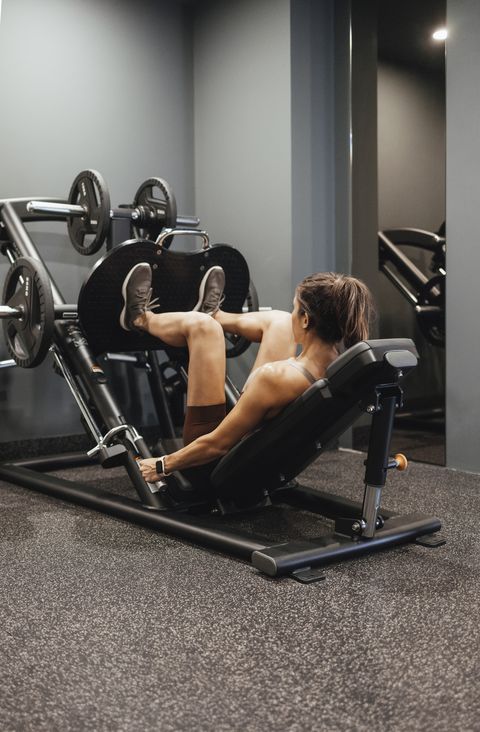 unrecognizable woman working out on a leg press machine at the gym