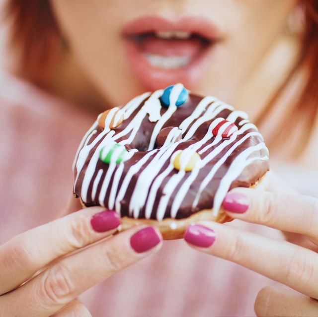 unrecognizable young woman eating delicious donut