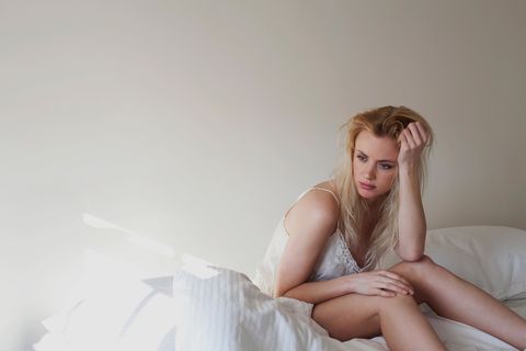 upset young woman sitting on bed