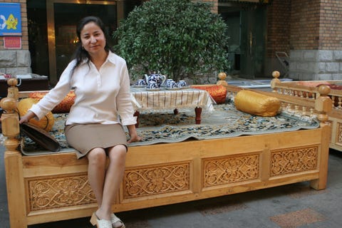 dawut at the big bazaar in urumqi, sitting on a supa, a traditional uyghur bed and table for eating
