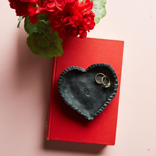heart shaped ring dish on red book with flowers
