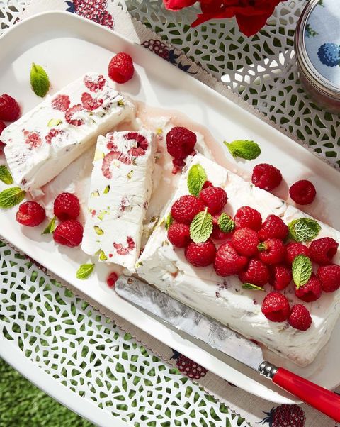 raspberry and pistachio semifreddo on a serving plate with fresh mint and raspberries on top