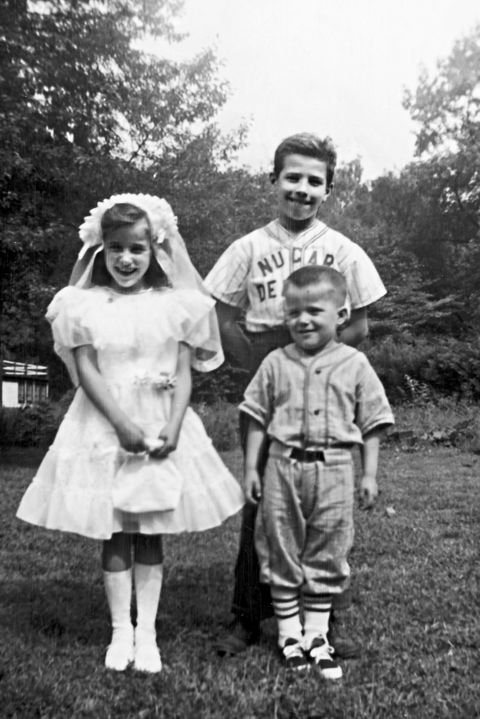 a seven year old valerie wearing her first communion dress stands alongside her brothers joe and jimmy