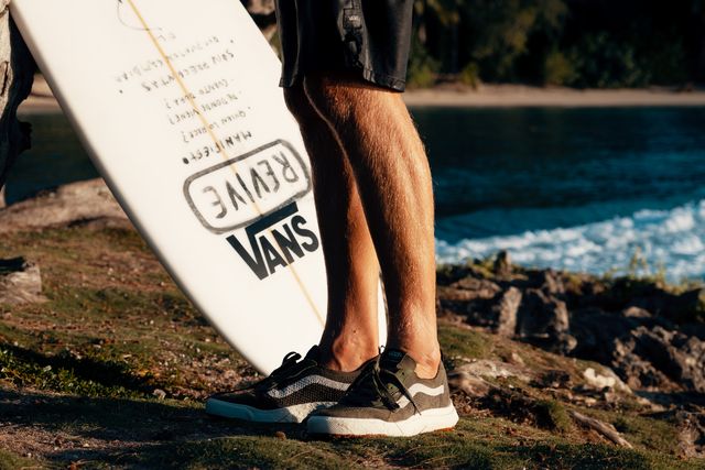 man wearing vans ultrarange™ vr3 sneakers carrying surfboard at the beach