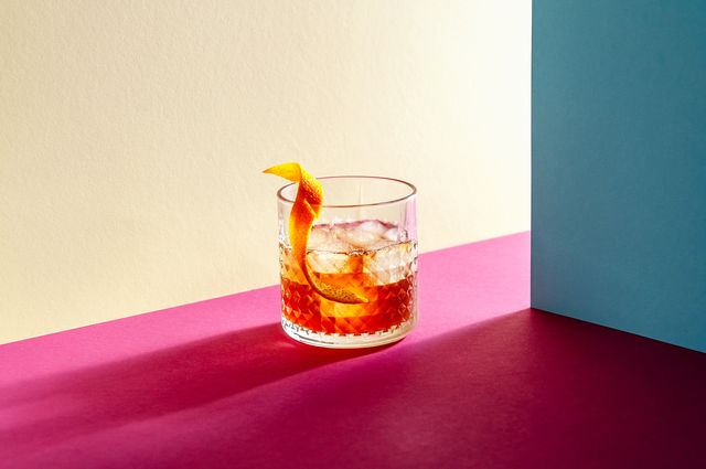 vaso de cristal con whisky, hielo y una cáscara de naranja