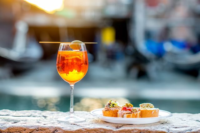 spritz aperol drink with venetian traditional snacks cicchetti on the water chanal background in venice traditioanal italian aperitif image with small depth of field