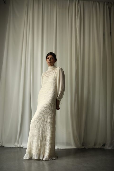 vestido de novia marion de corte recto, confeccionado en un tejido con pequeños plisados y fruncidos con toques de brillo, cuello perkins y mangas voluminosas de gasa de panambi