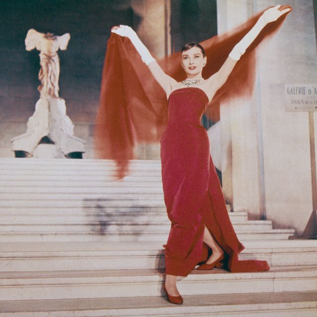 audrey hepburn walks down the stairs of the louvre in a red dress in a scene from the film 'funny face'