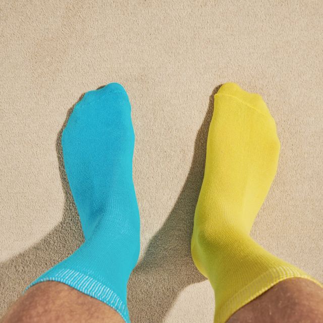 pov view of mans feet wearing odd socks, blue and yellow