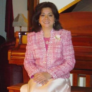 vilma kari in a pink blazer sitting at a piano