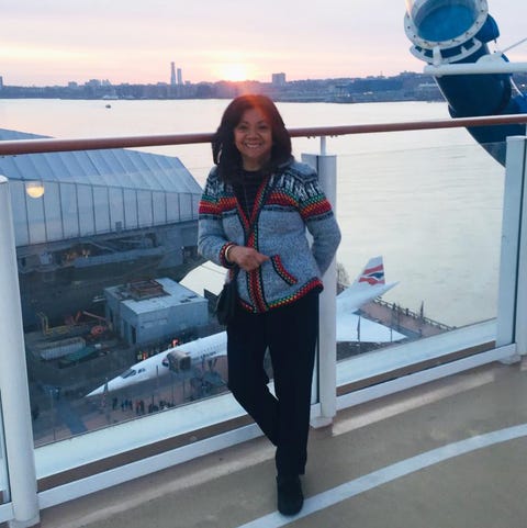 vilma standing in front of a sunset wearing a grey cardigan with embroidery