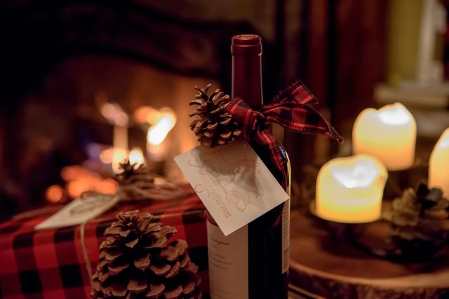 romantic bottle of wine and gift on table by fireplace on christmas