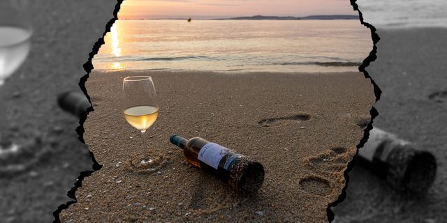 botella y copa de vino blanco rías baixas sobre la arena de la playa