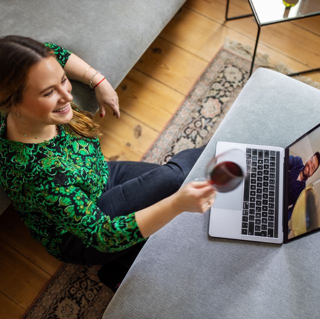 first date questions to ask woman toasting a glass of wine with man over video call on her laptop during online date