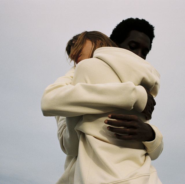 twee mensen omhelzen elkaar gekleed in hoodies in de buitenlucht