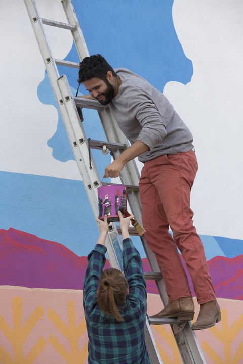 couple painting mural wall outdoors