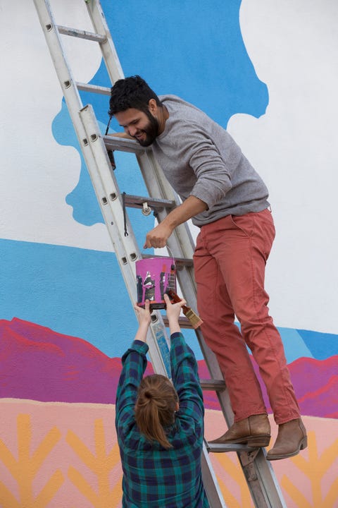 couple painting mural wall outdoors