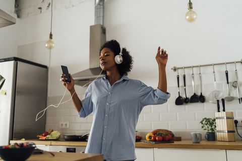 Woman dancing and listening music in the morning in her kitchen
