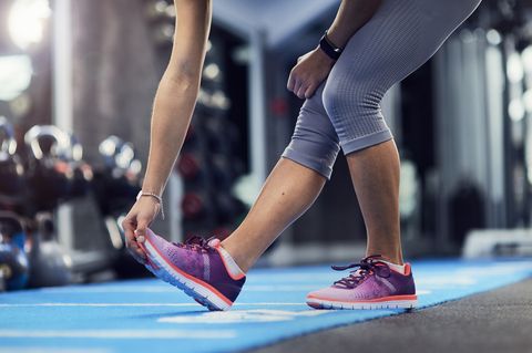Waist down view of young woman touching toes on gym mat