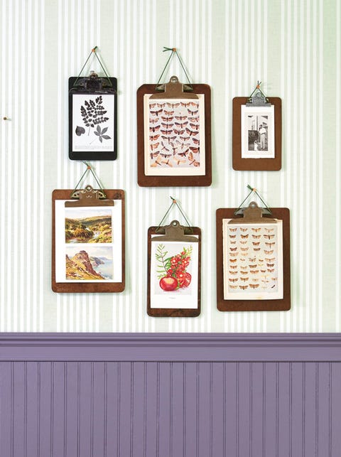 six different sized clipboards hang on  a wall with art clipped to them