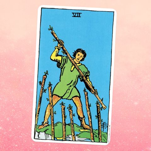 the Seven of Wands, showing a person dressed in a green tunic and yellow leggings, holding a stick as if ready to fight six more sticks are raised in front of them