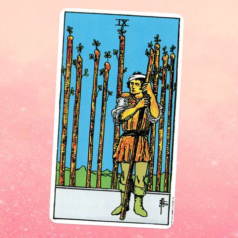 the Nine of Wands tarot card, showing a person in a tunic holding a wooden staff with eight others behind them