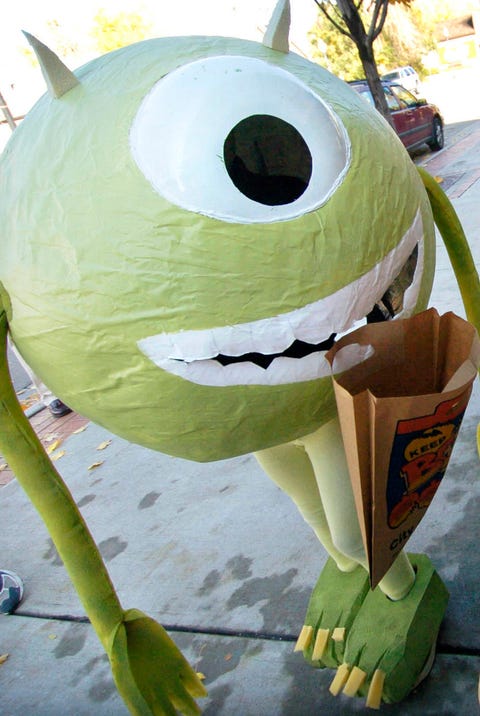 LOUISVILLE, COLORADO, OCTOBER 31, 2005--Warren <cq> Harris <cq> ,10, dressed as the one-eyed monster character named Mike Wazowski <cq> from the Disney animated movie Monsters Inc., looks over a candy selection while walking in the annual Louisville Eleme mike wazowski