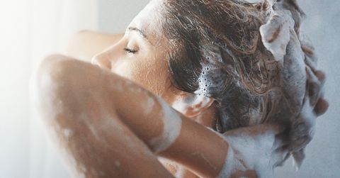 Mujer lavándose el pelo en la ducha.